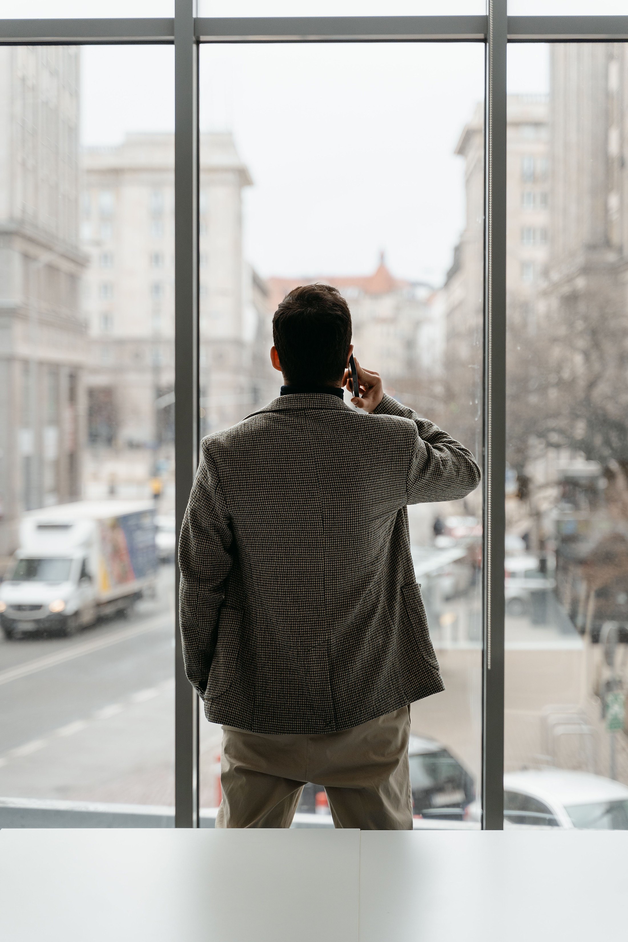A man standing by a window on the phone representing principals