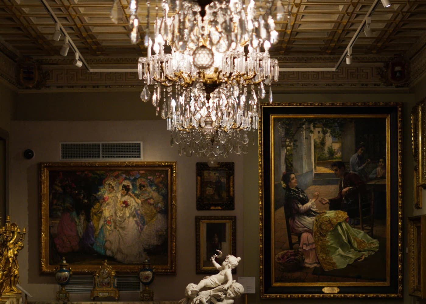 Gallery interior with framed paintings and sculpture representing art and collections