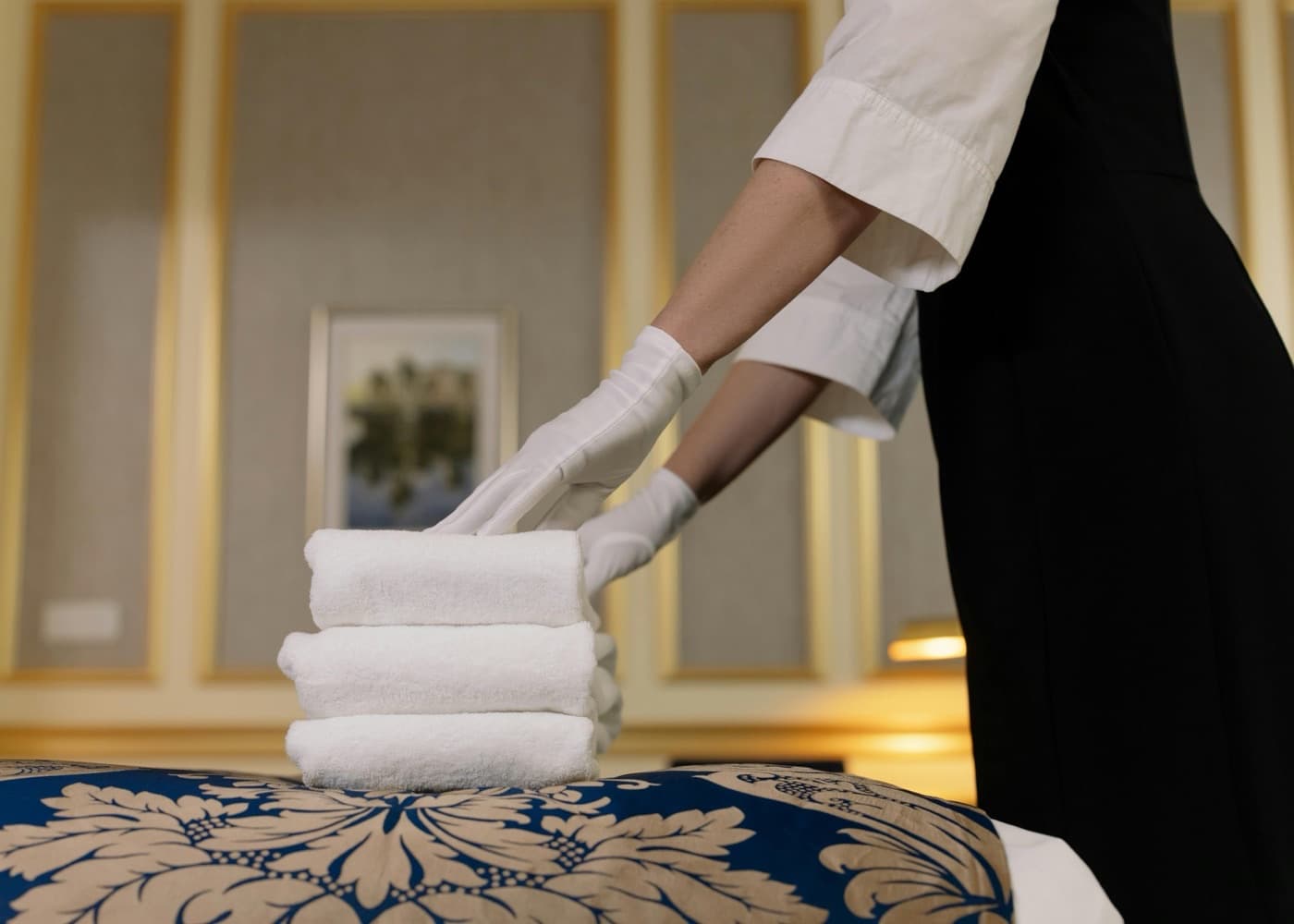 Household staff member arranging folded towels representing household staffing